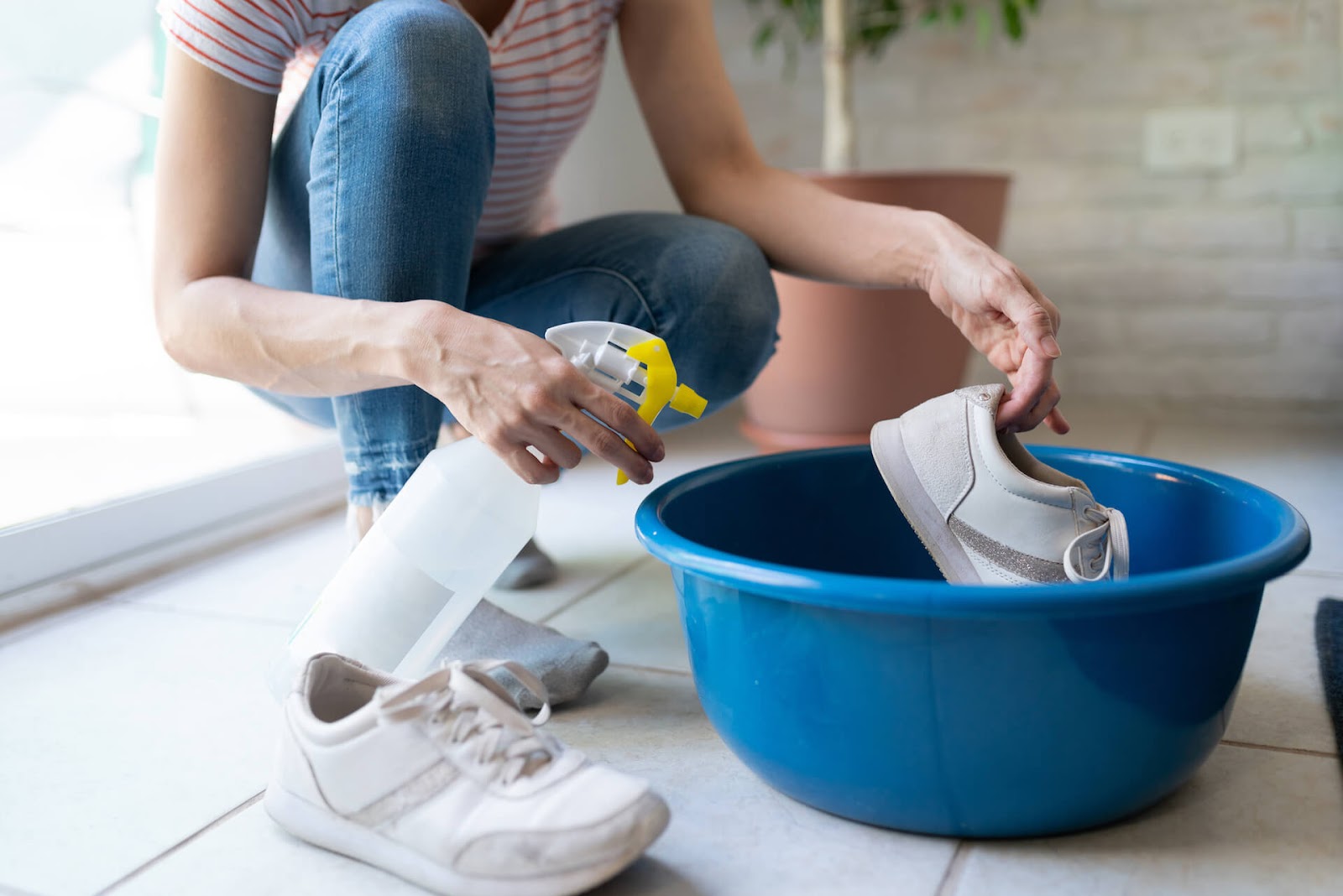 Woman spraying her shoes in a big, blue bucket