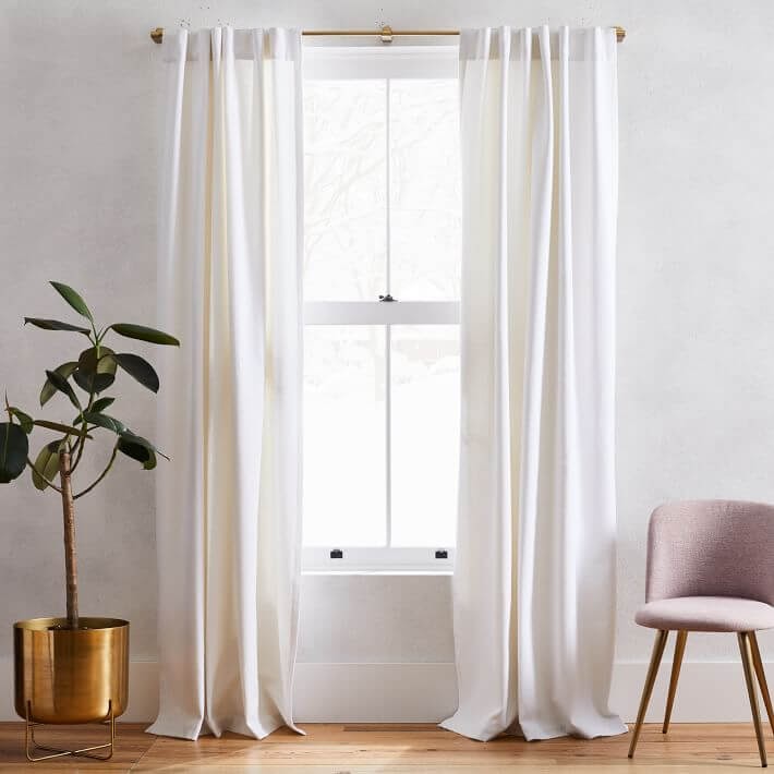 White curtains hanging over gold curtain rod