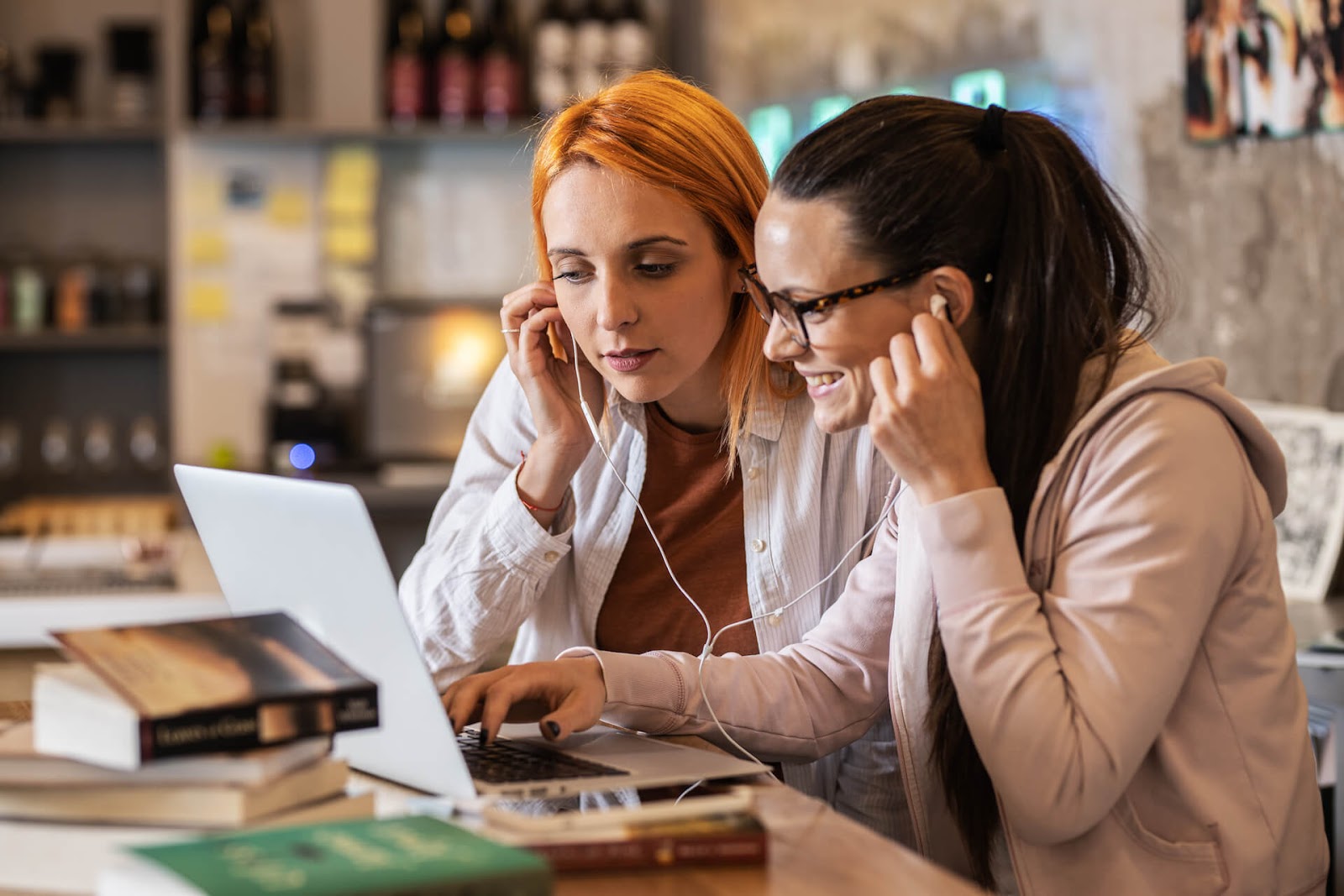 Two women sharing headphones as they talk about a book with someone online