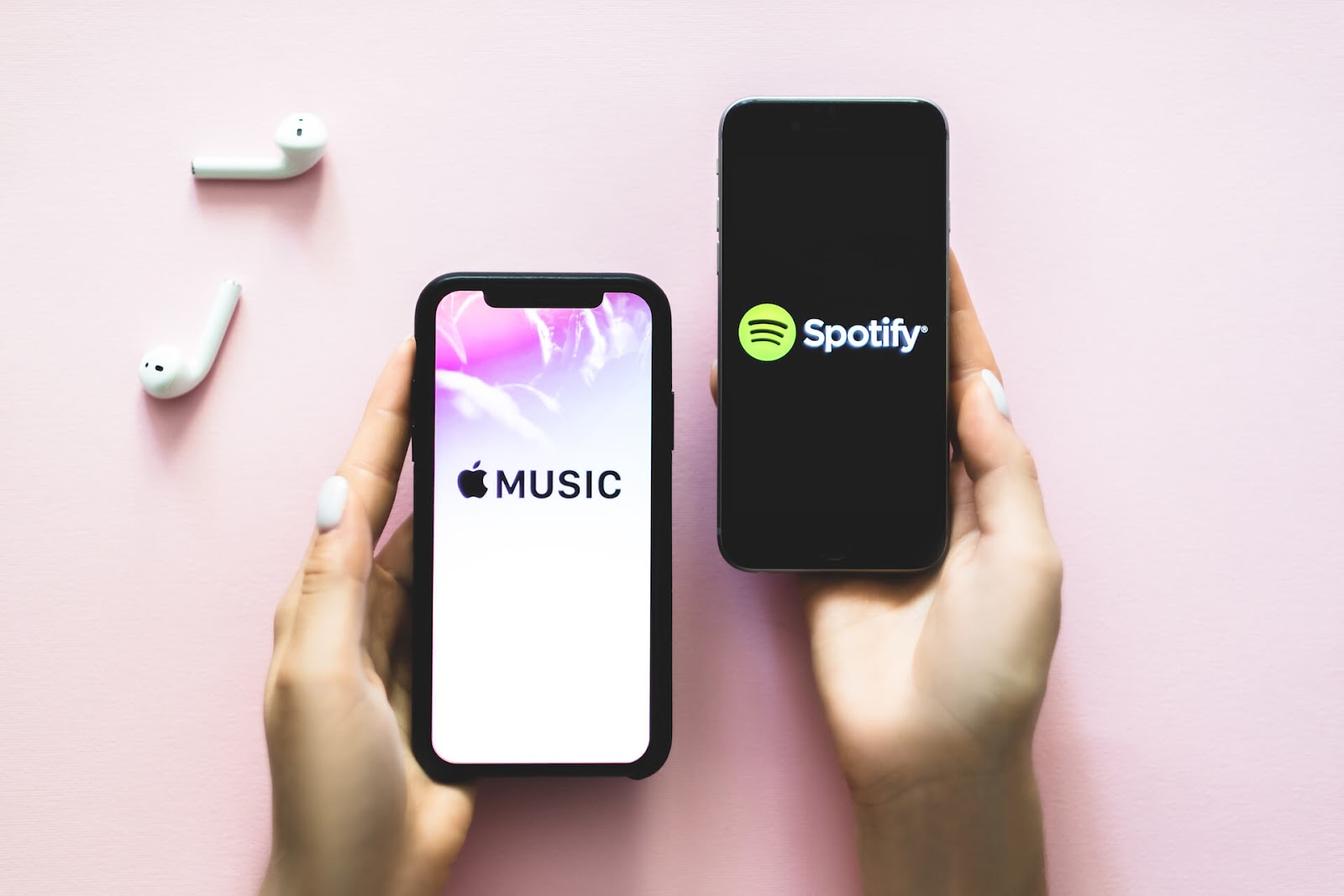 Woman holding a phone that says Apple music and one that says Spotify