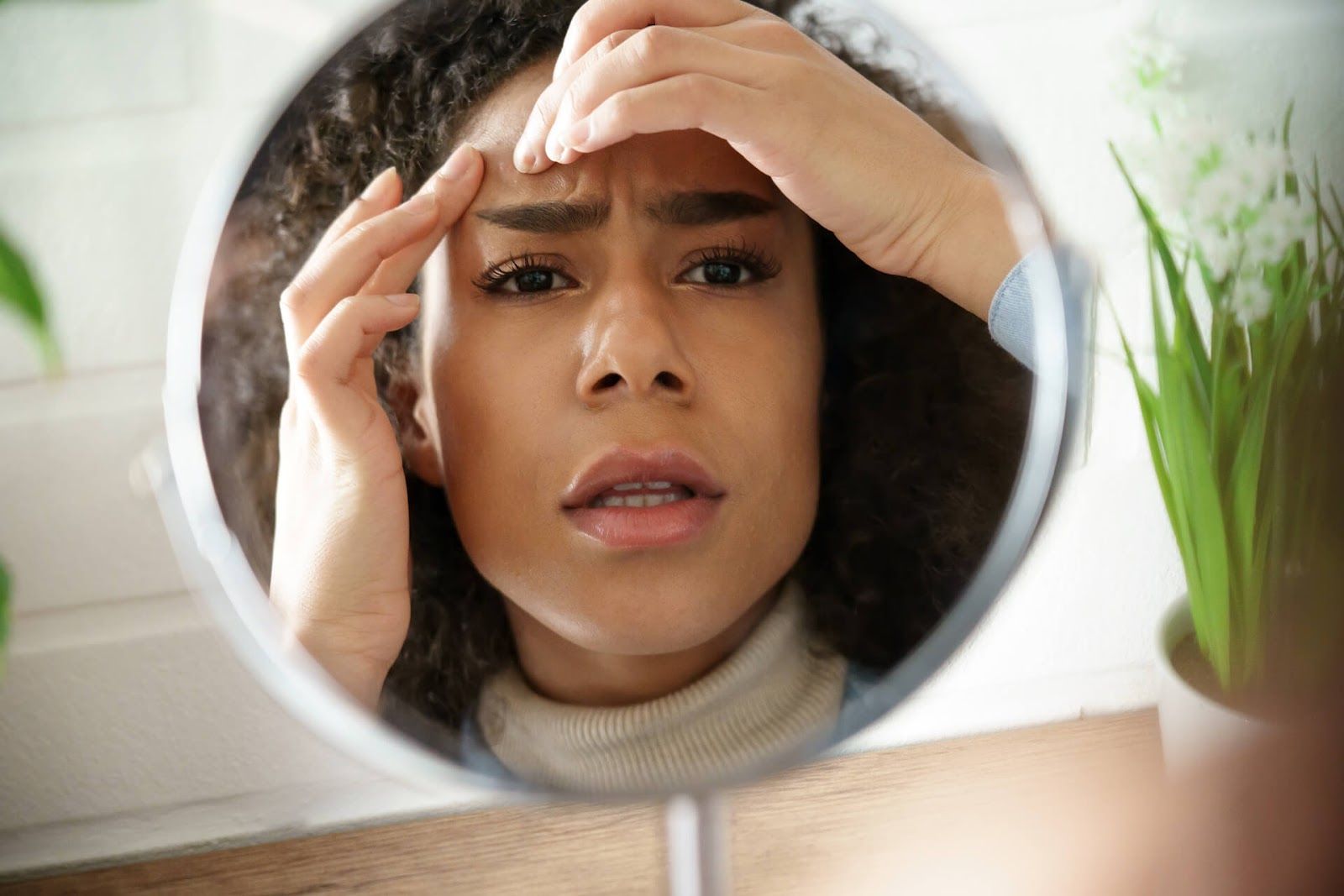 Woman looking unhappily at her skin in a mirror