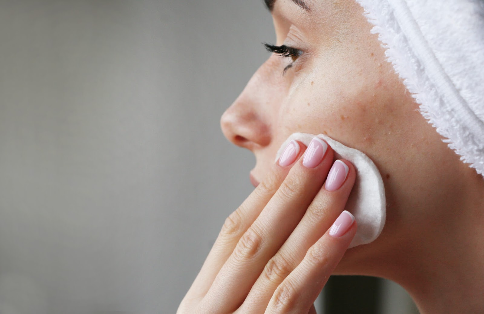 Woman rubbing her face with a cotton pad after a shower