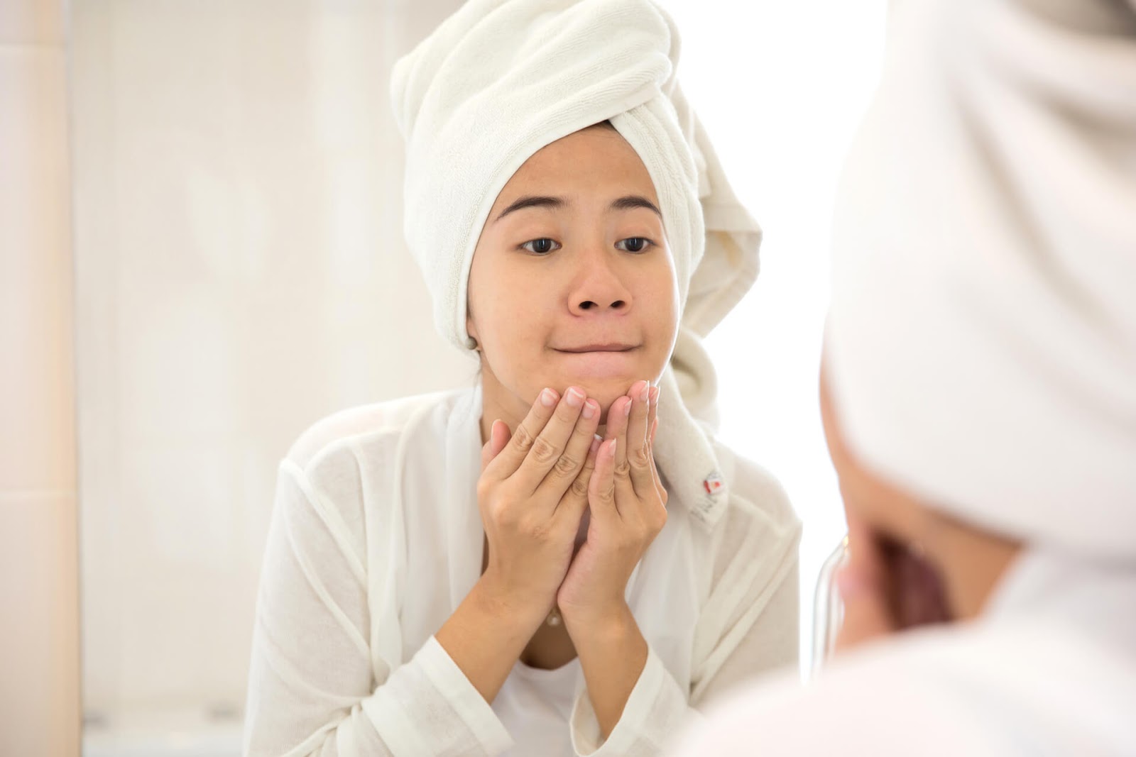 Young woman looking at her chin in the mirror
