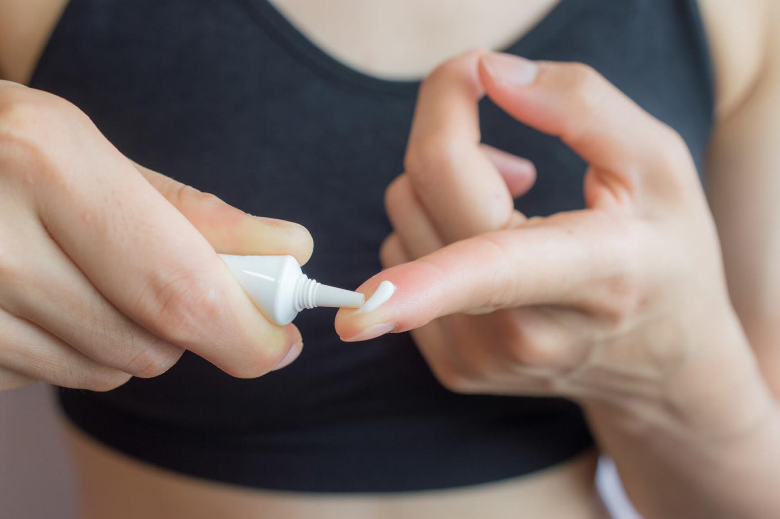 Woman putting cream on her finger to treat comedones