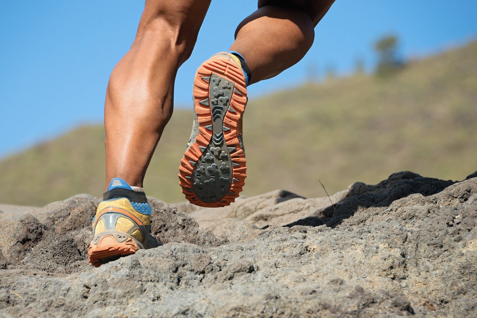 Close up of man's calves as he runs up rocks