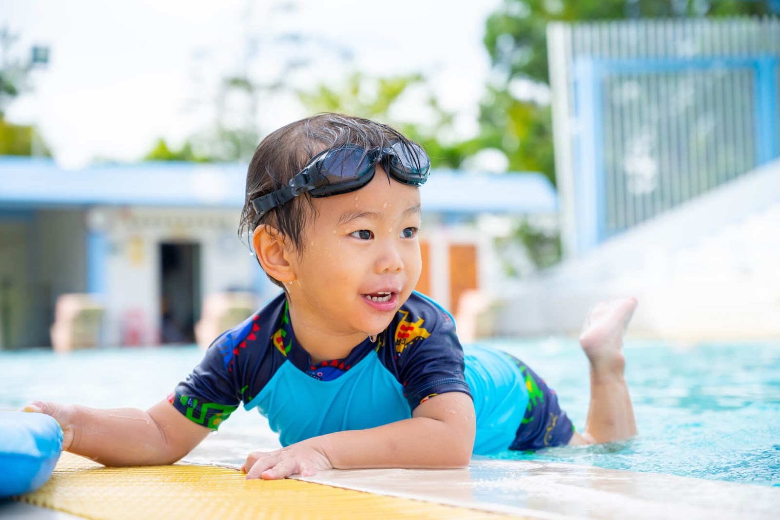 Young boy playing on his belly in the water with a swim shirt on