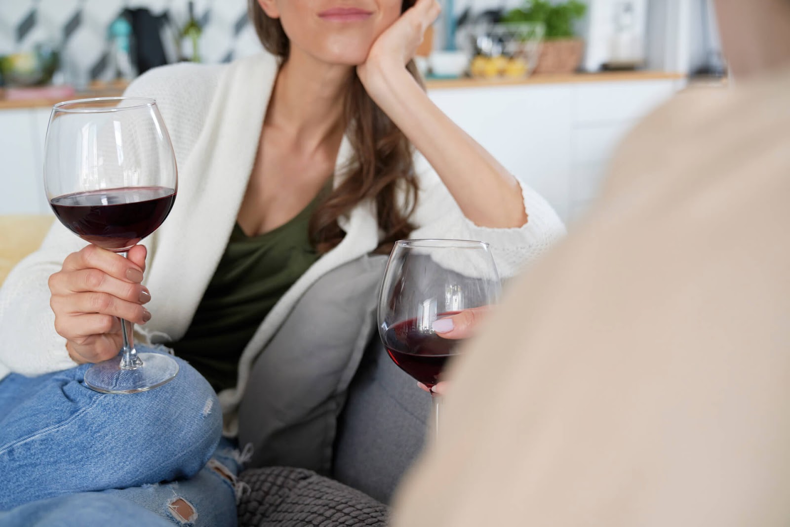 Two women drinking wine on the couch and talking