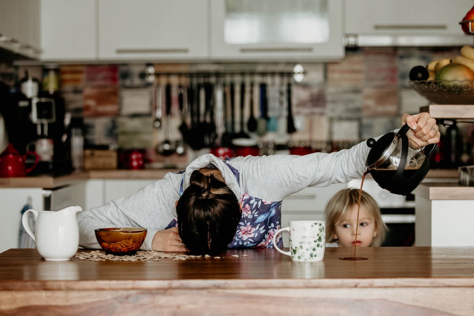 Tired mom pouring coffee on the counter as she misses her cup
