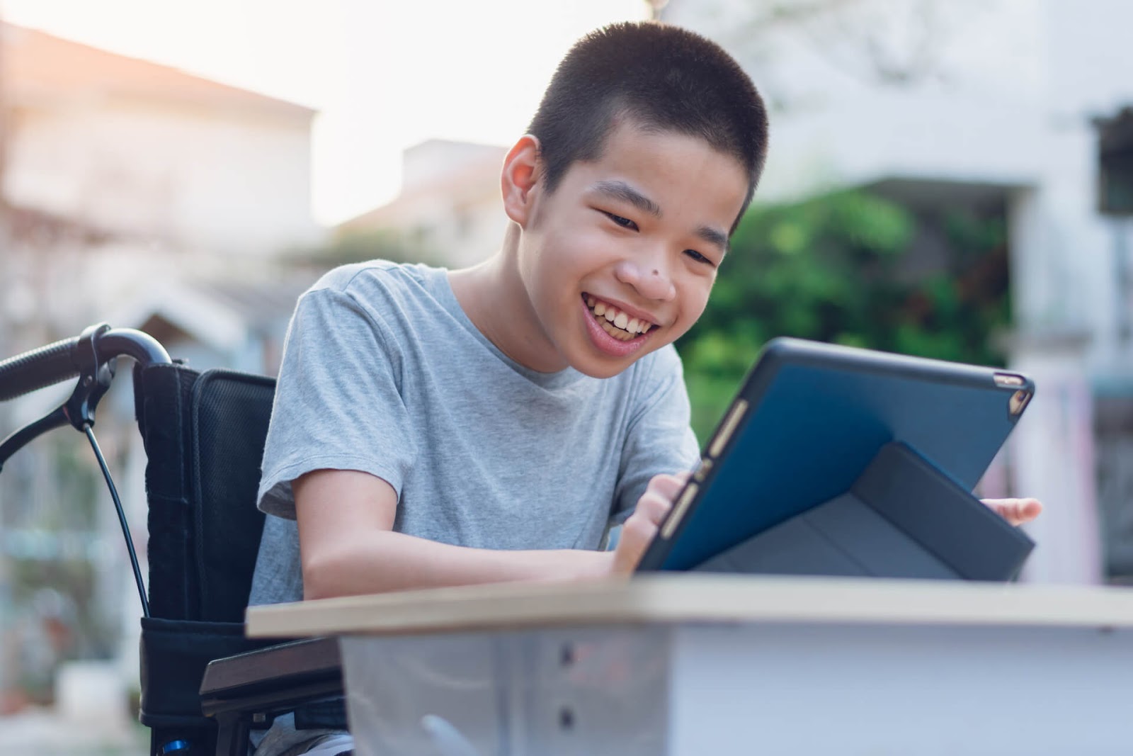 Young boy playing on his tablet from his wheelchair