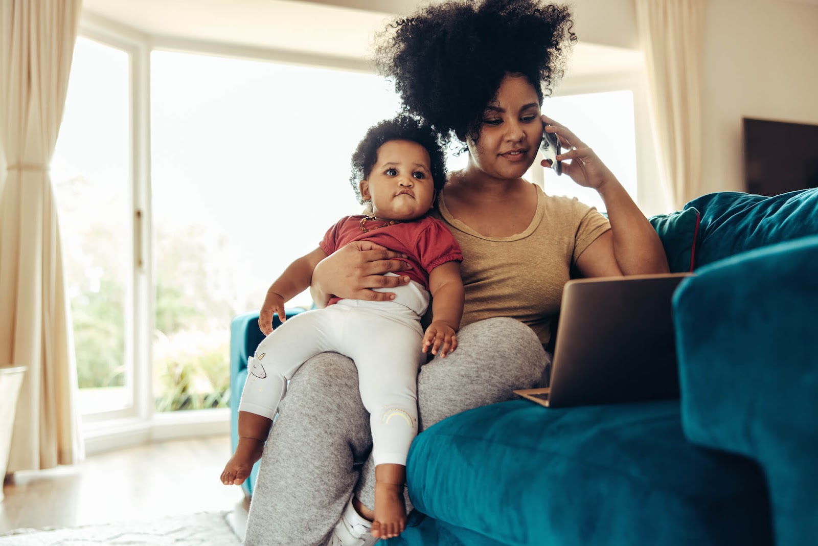 Woman hustling and bringing in some income from her couch with her toddler in her arms