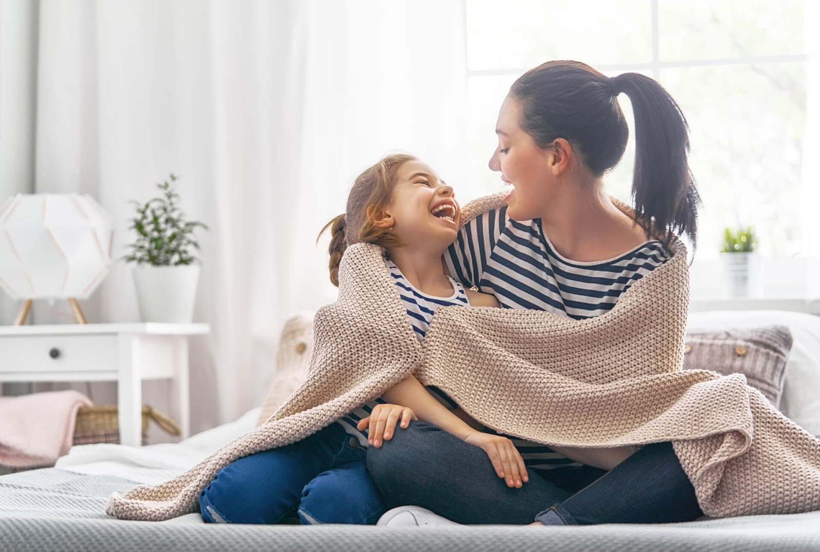 Mom and daughter wrapped up in a blanket laughing