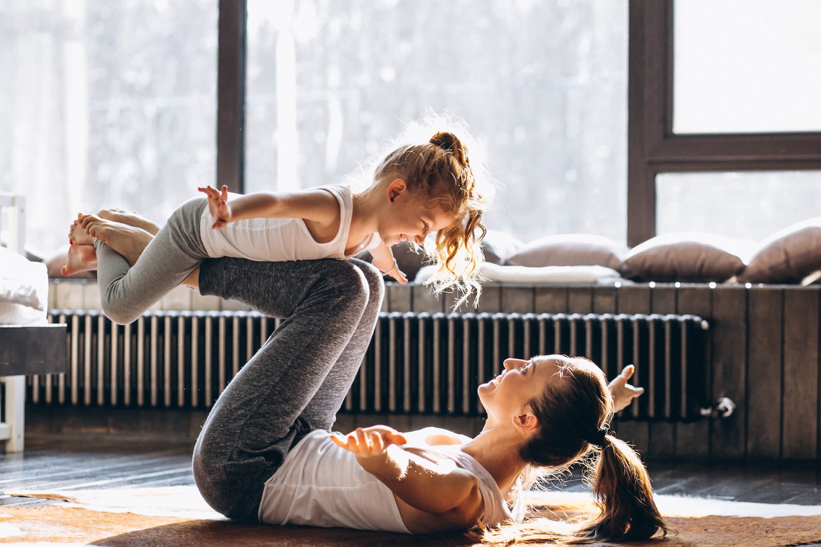 Woman doing chest opening yoga with her daughter