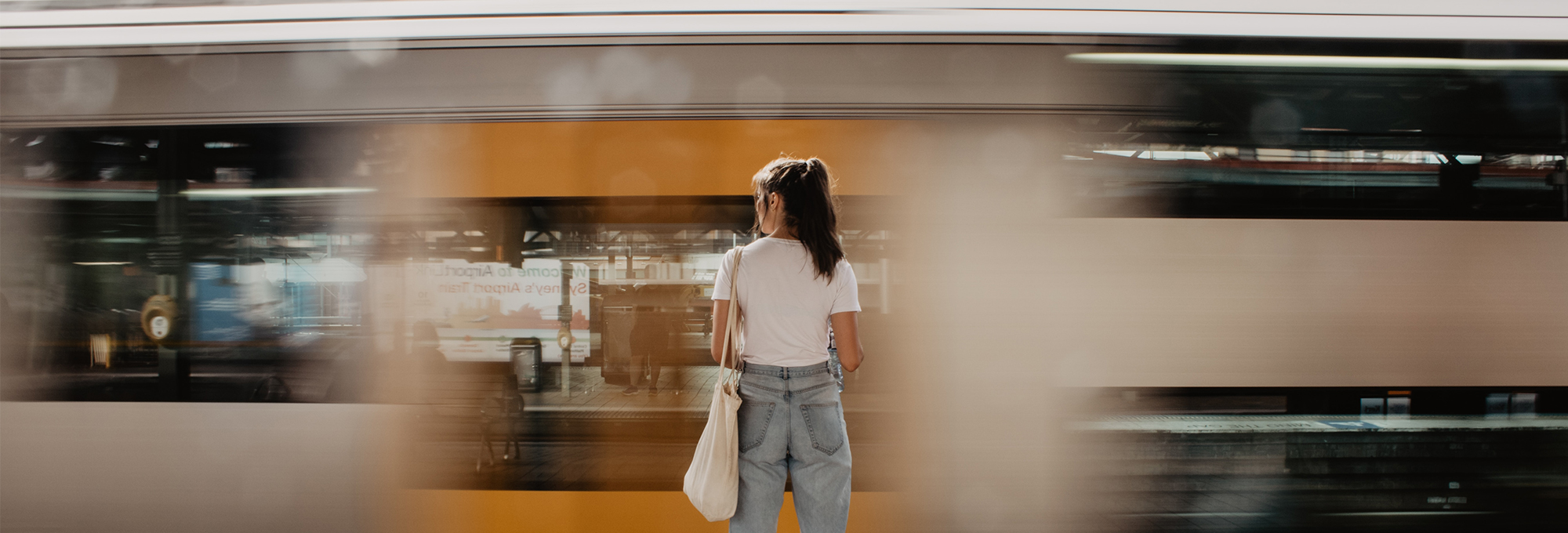 Back of a woman waiting at a train station for a train