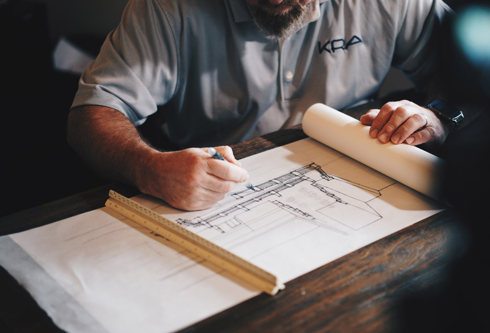 Man drawing building on trace paper with scale