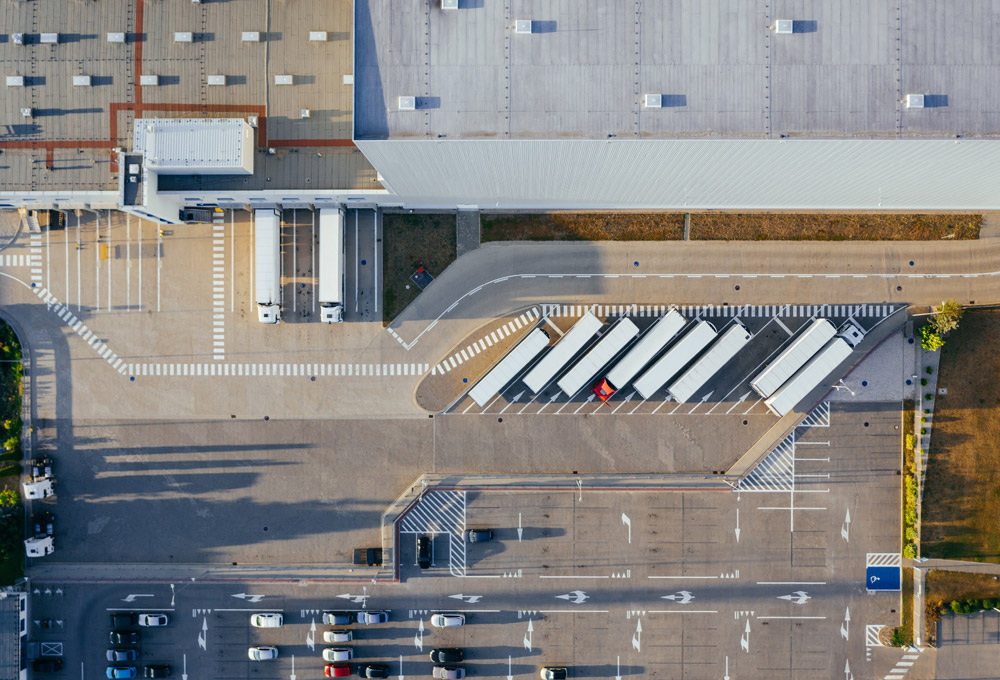 Aerial view of semi-trucks parked outside of a large warehouse