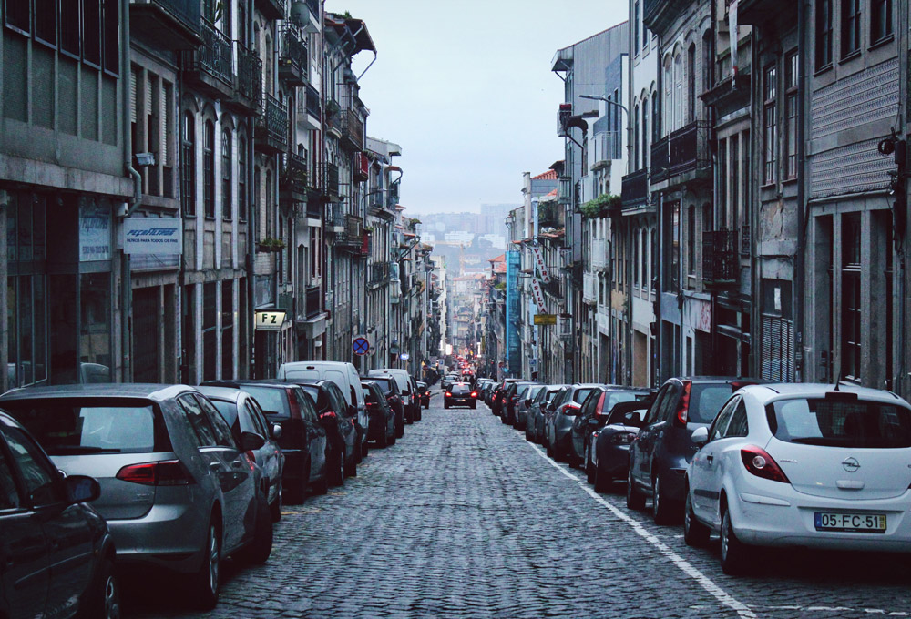 Narrow downhill road in Porto, Portugal with cars parked on both sides