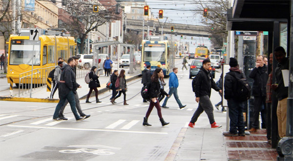 people corssing the street with light rail in Seattle