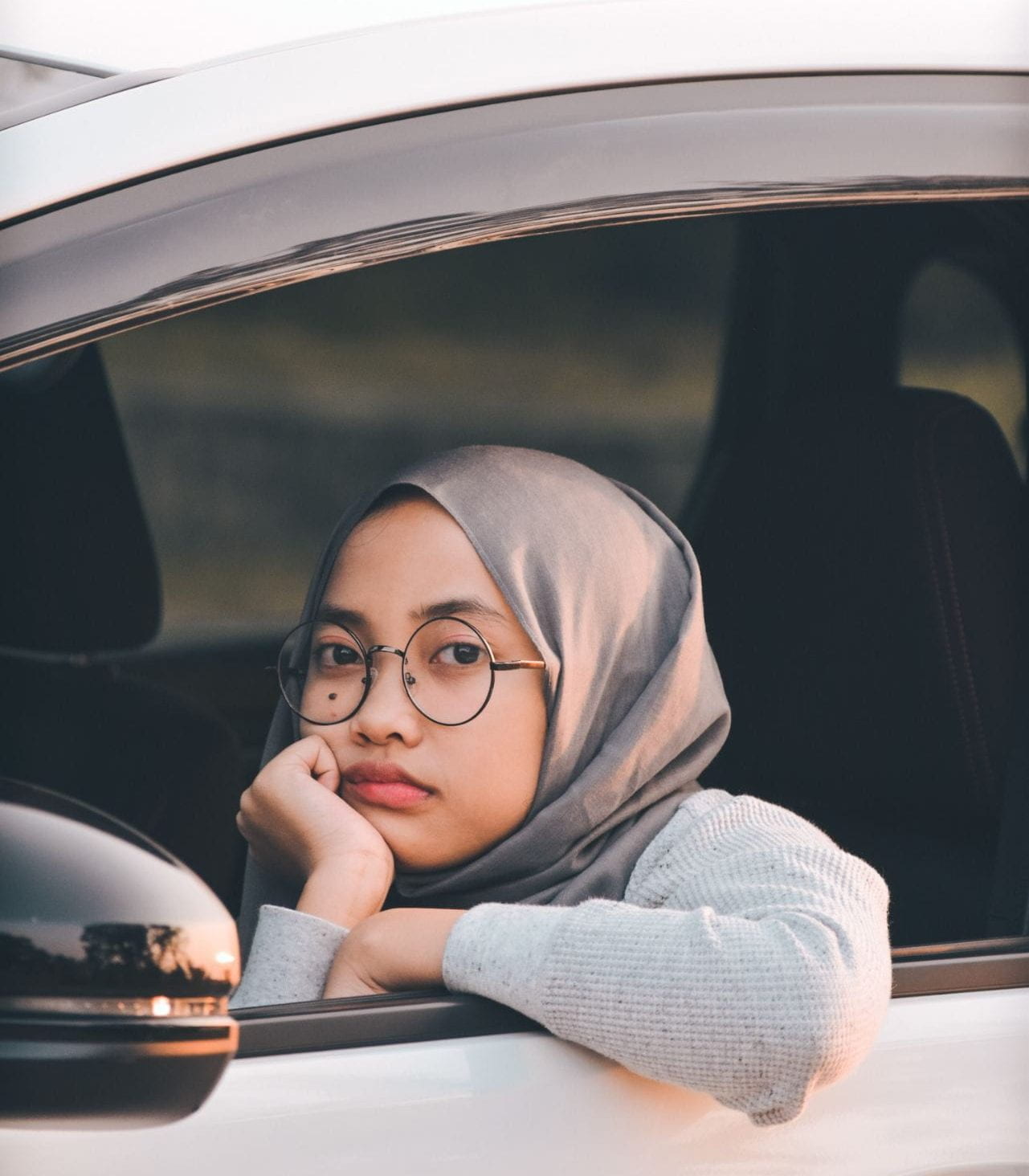 woman sitting in the front seat of a car with her arm out of the window