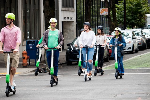 people riding electric scooters on a street