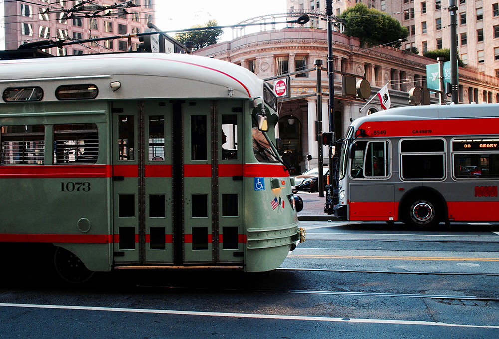 Light rail train passes city bus on a street