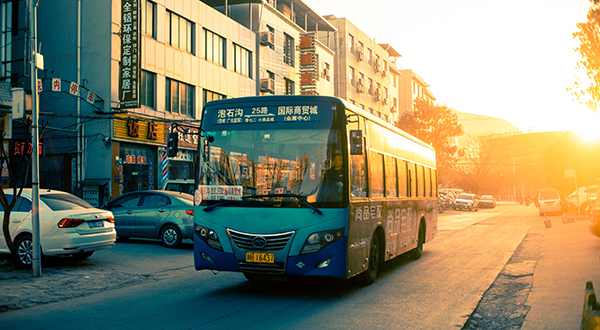 City bus driving down paved road at sunset