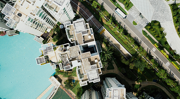 Aerial view of apartment high-rise buildings next to a pool on one side and a city street on the other