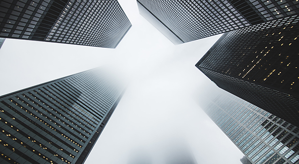 View looking up at tall buildings with some disappearing into fog