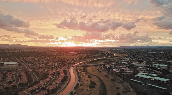 Drone image of sprawling city in Arizona with canal at sunset