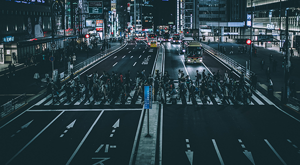 Pedestrians crossing a busy city street in a crosswalk at night