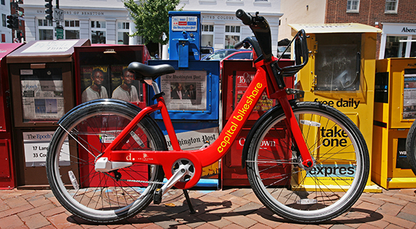 Bikeshare bike on sidewalk in front of newspaper boxes