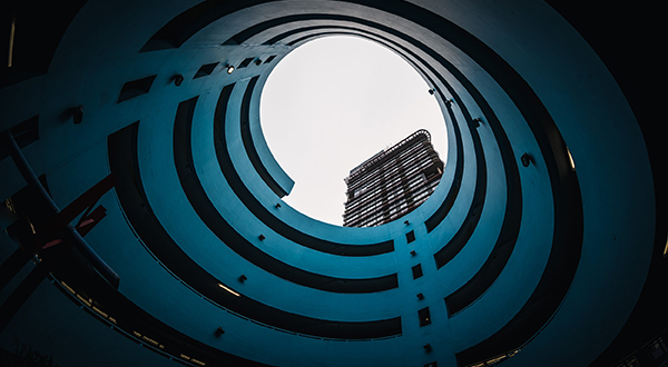 Looking up from interior gap of a spiraling parking garage toward the sky