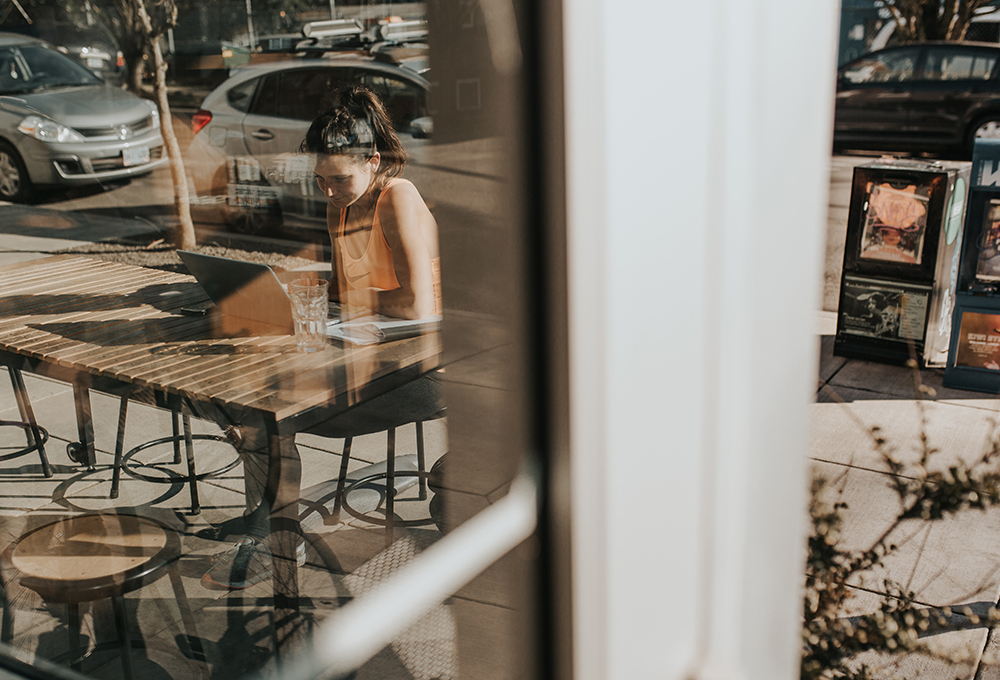 Woman sitting at table, viewed through glass window