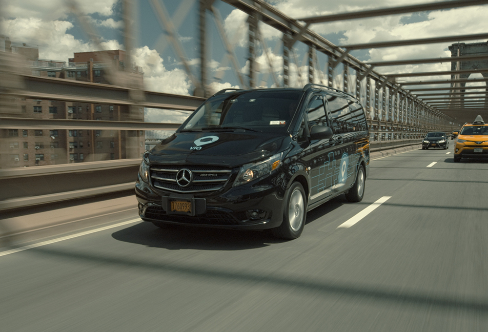 Black microtransit van driving across bridge