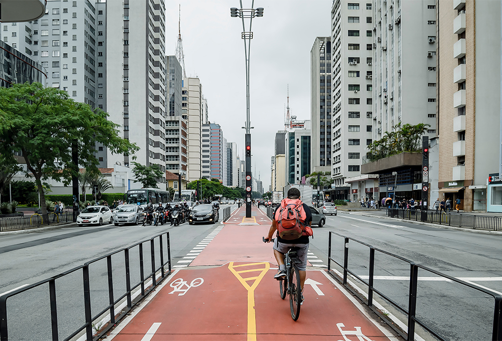 Bicyclist riding on protected red bike lanes in the center of busy street in Sao Paulo, Brazil