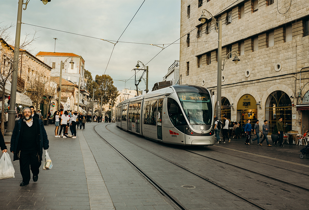 people walking next to light rail and buildings in Jerusalem