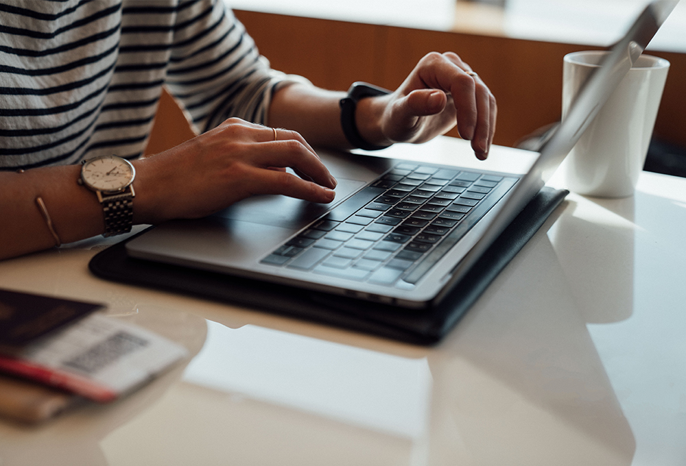 Person using laptop with mug in the background