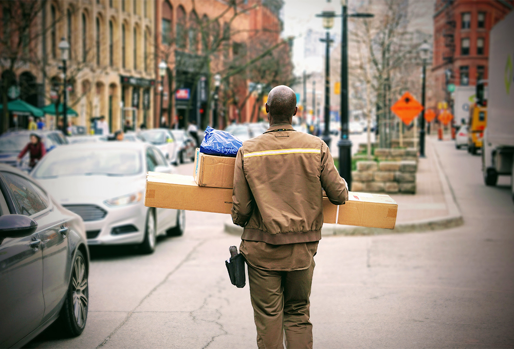 Delivery man carrying packages through city