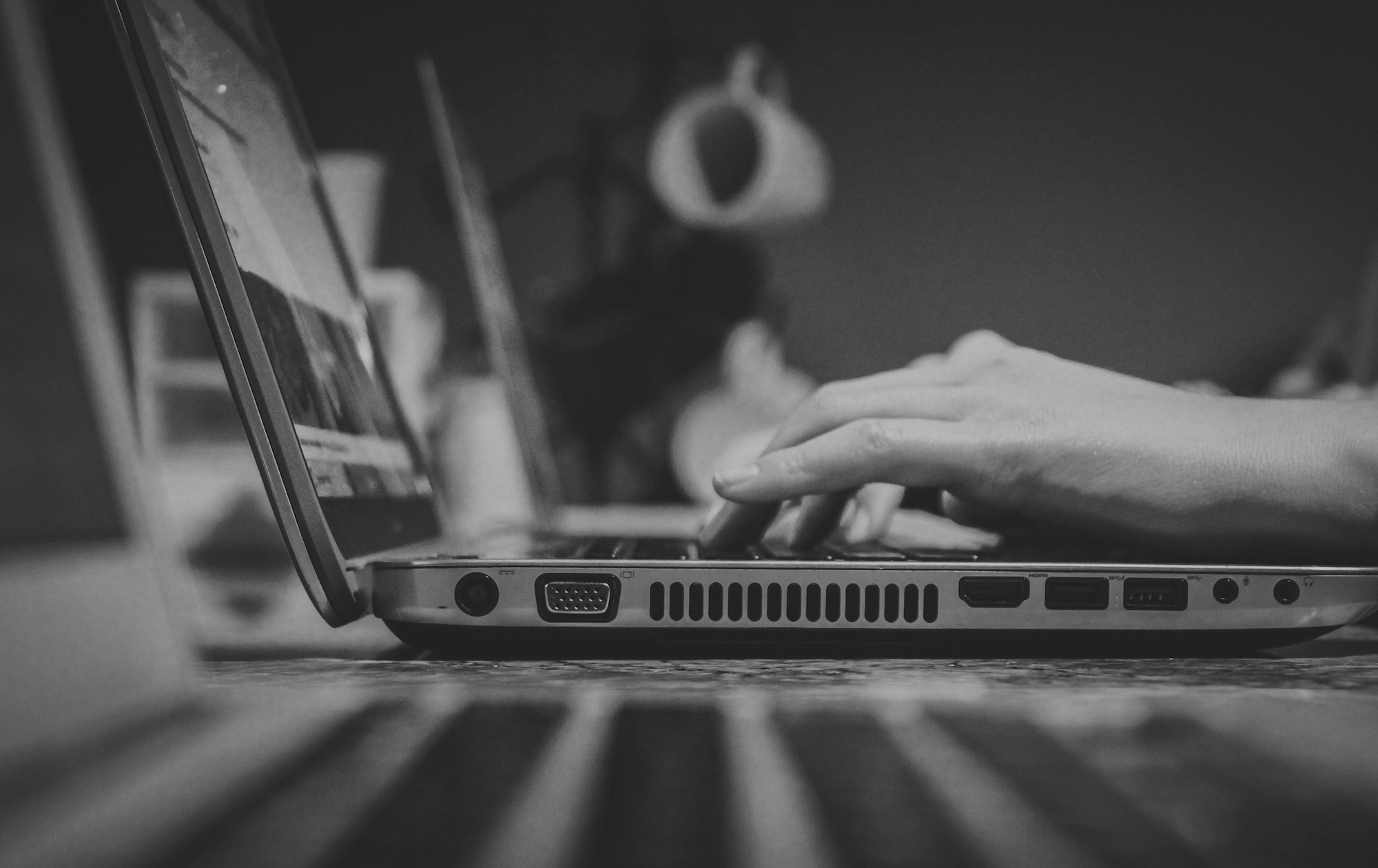 Black and white photo of hands typing on a laptop.