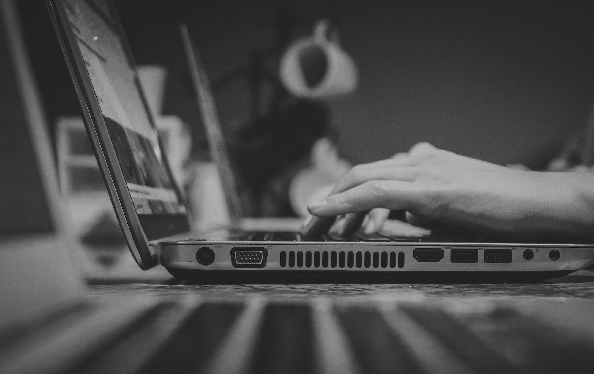 Black and white photo of hands typing on a laptop. 