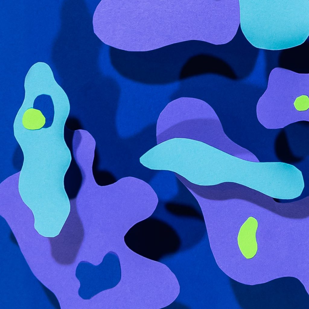 This is a photo of an abstract art piece done in varying shades of blue. The background is dark blue and there are amorphous blob-shapes in royal blue and aqua at different heights, which throw shadows on the image. There are small dots of lime green accenting the blob-shapes.