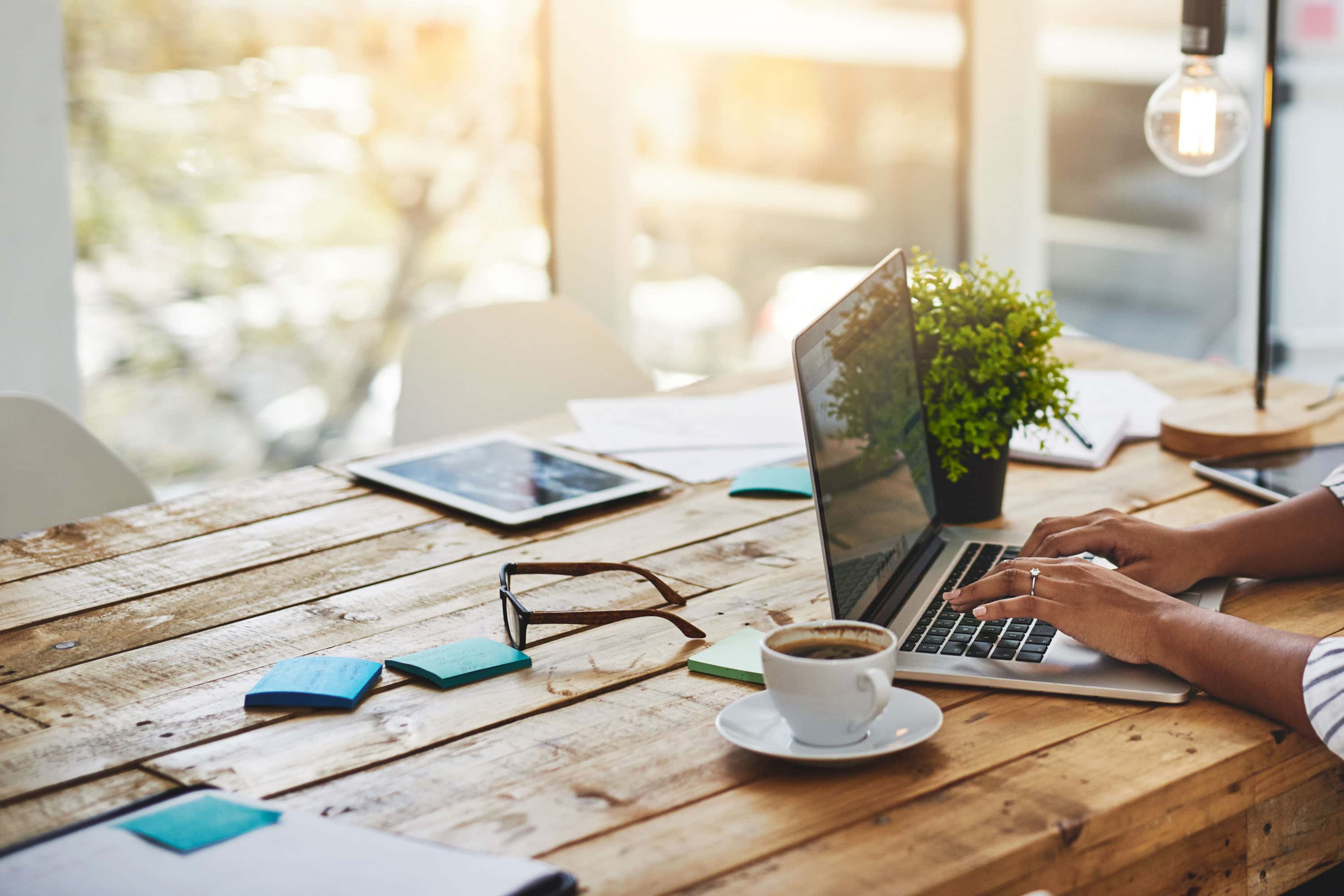 A woman drinks coffee and uses her computer.
