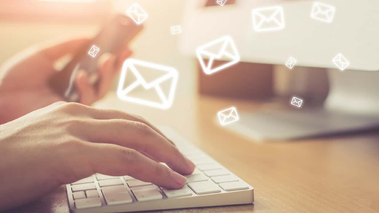 Close up photo of hands typing with animated white envelopes flowing from keys