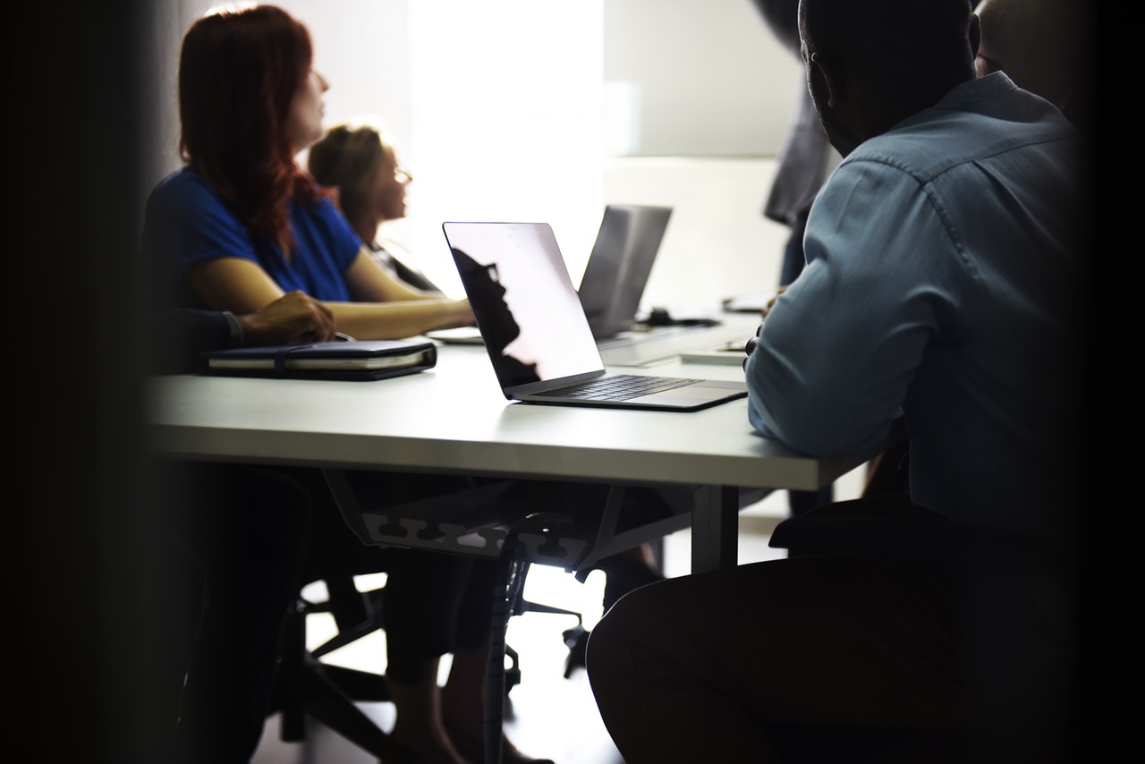 Group of people with laptops sitting at a table