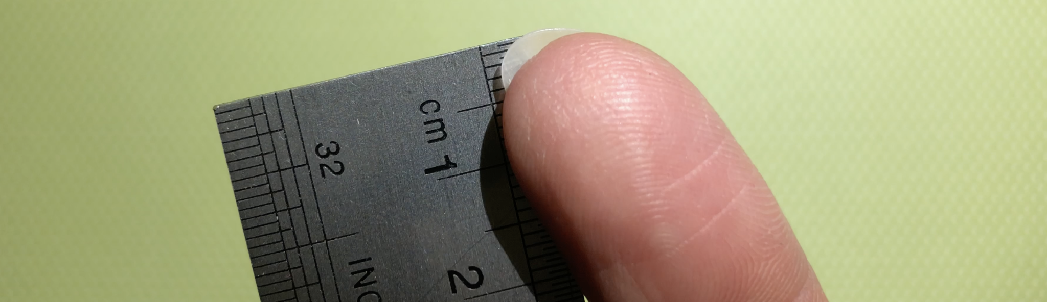 Measuring a fingernail by looking at the underside and using a ruler.