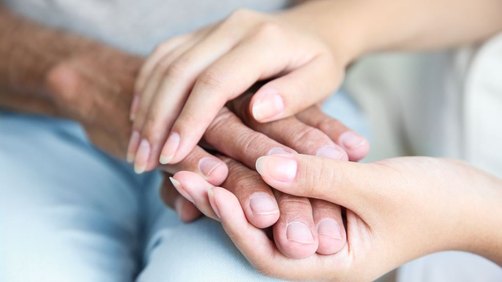 Carer holding hands of an elderly patient