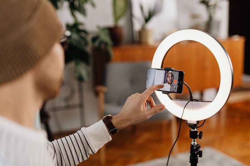 A man recording himself with a cellphone and backlight
