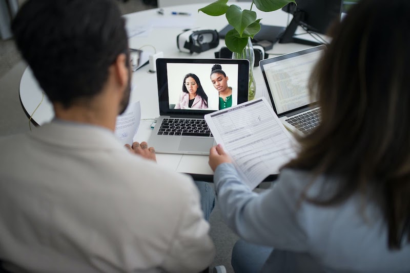 Two candidates being video interviewed by two recruiters