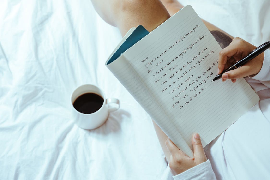 Someone writing in journal / diary with a cup of coffee