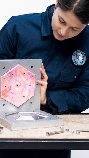 Woman opening a mould with recycled product inside