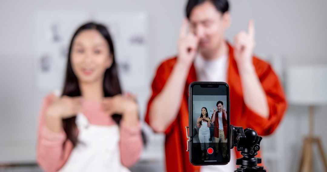 Young couple tiktoker creating their dancing video with smartphone camera and tripod